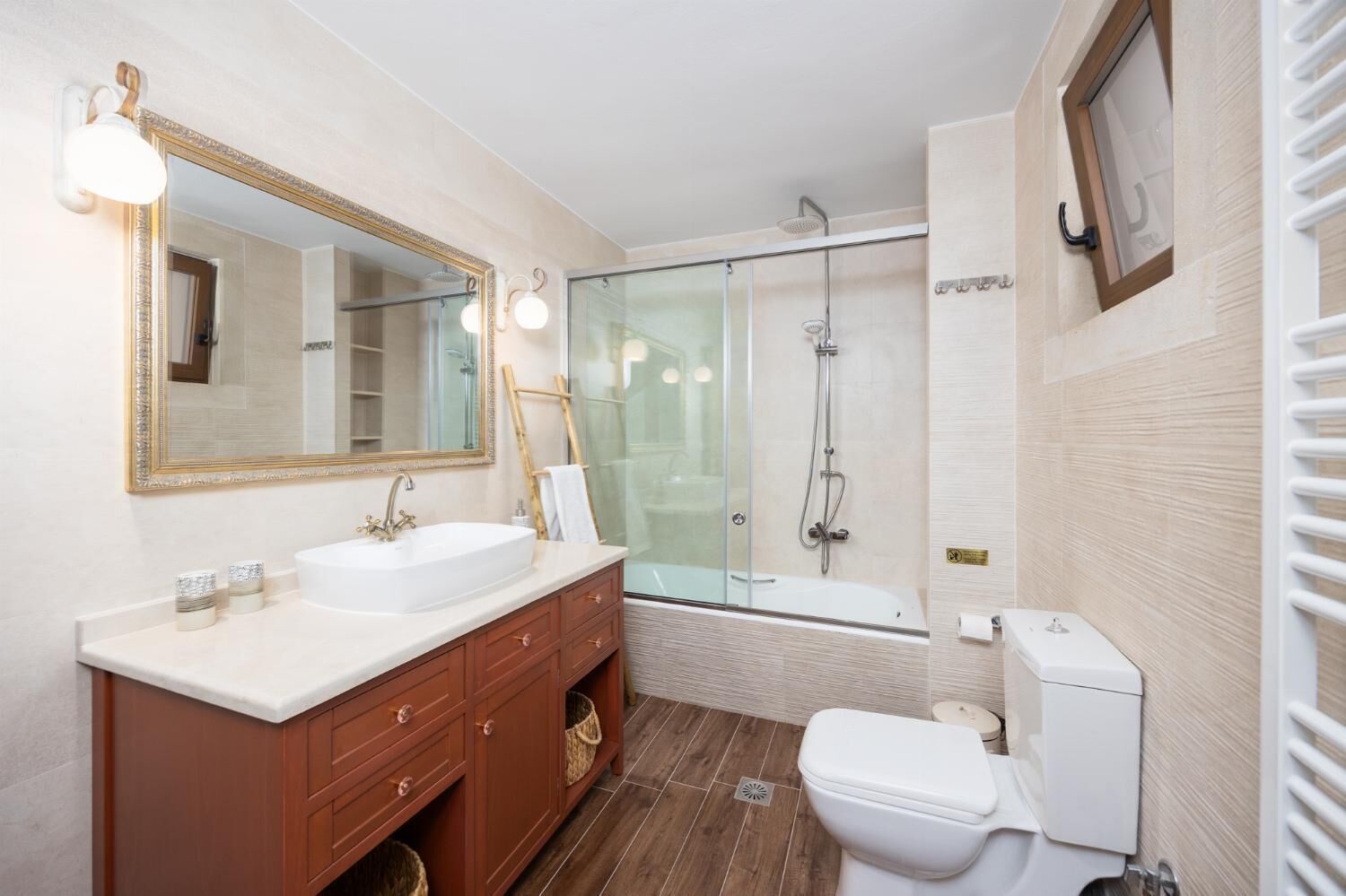 A modern bathroom with a large mirror, a sink, a toilet, and a glass-enclosed shower.