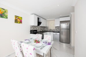Enjoy meals in this well-equipped kitchen with a dining table, refrigerator, and modern cabinetry.
