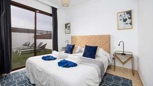 A hotel room with a large bed, a view of the outdoor area, and a small side table. - Villa Cindy - Three Bedroom Villa, Sleeps 6 (Playa Blanca)