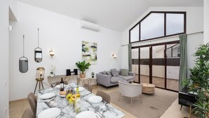 A modern dining area with a marble table set for four, a grey sofa, and a balcony with a view. - Villa Cindy - Three Bedroom Villa, Sleeps 6 (Playa Blanca)