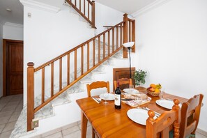 Ein Essbereich mit einer Holztreppe, Marmorstufen und einem für zwei Personen gedeckten Tisch mit Tellern, Gläsern und einer Weinflasche.