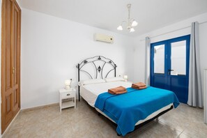 A bedroom with a bed, nightstand, and an air conditioning unit.