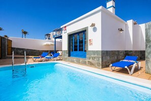 Una piscina amb gandules blaves i un edifici blanc amb detalls blaus.