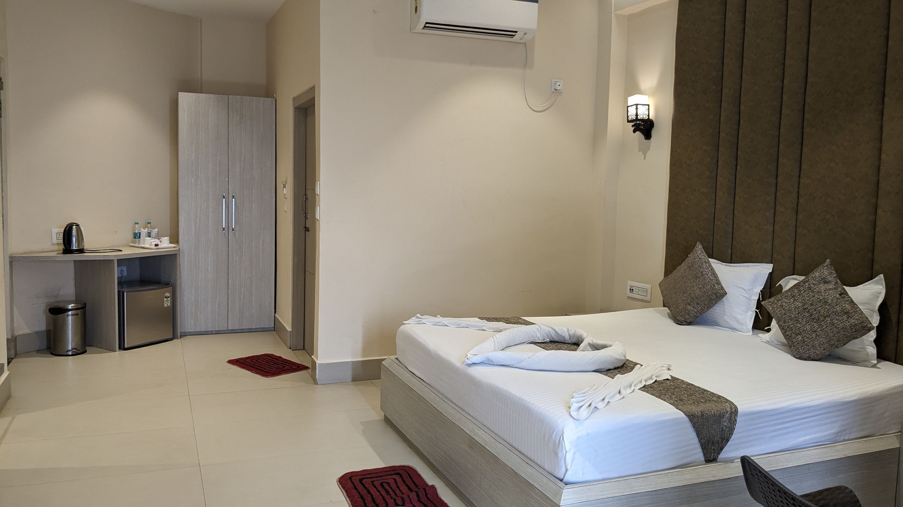 A hotel room with a bed, bedside table, and a desk with a chair.
