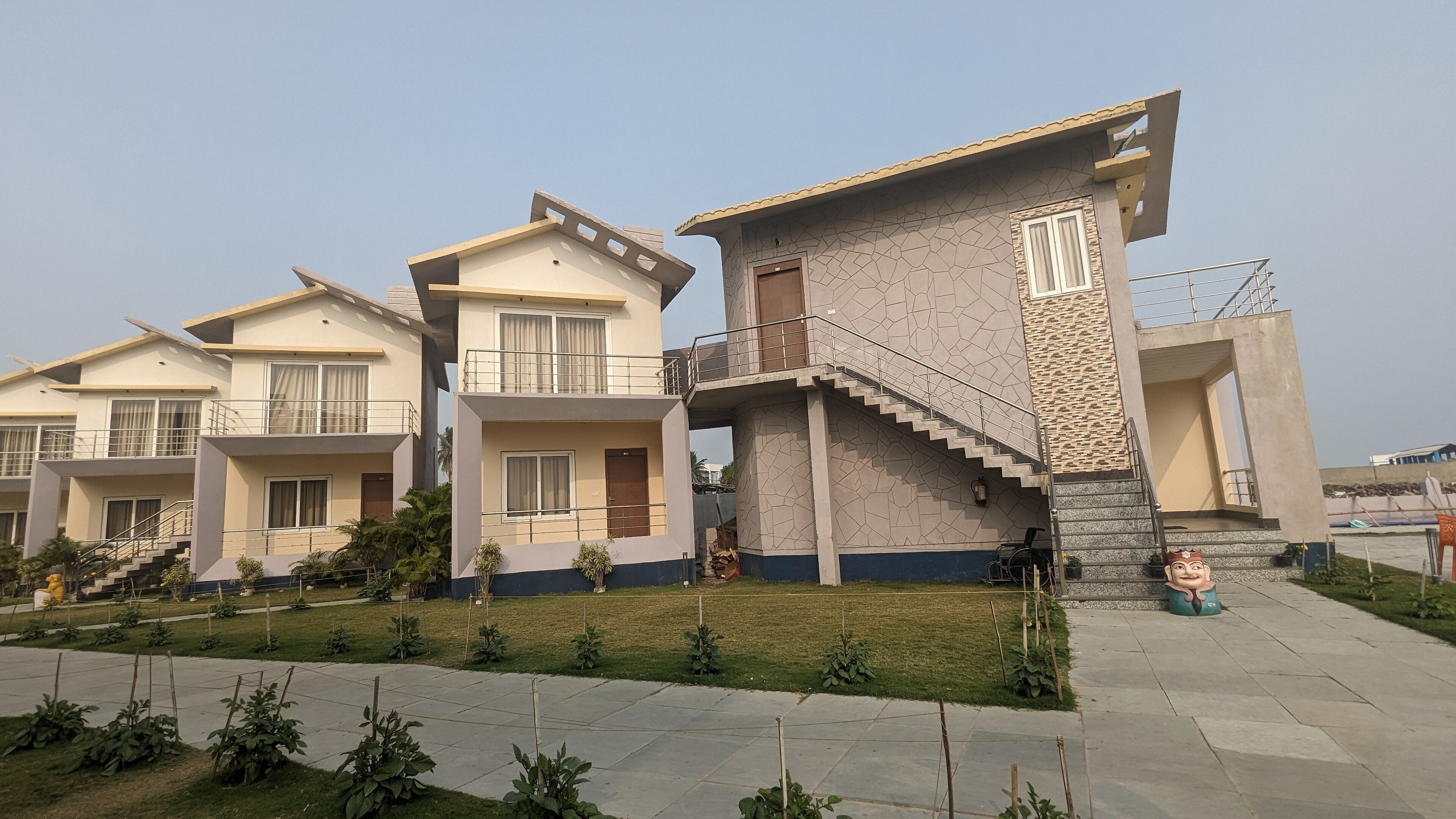 A modern residential building with multiple balconies, a staircase, and a well-maintained garden area.