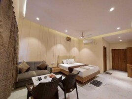 A modern hotel room with a sofa, a bed, a desk, and a chair.