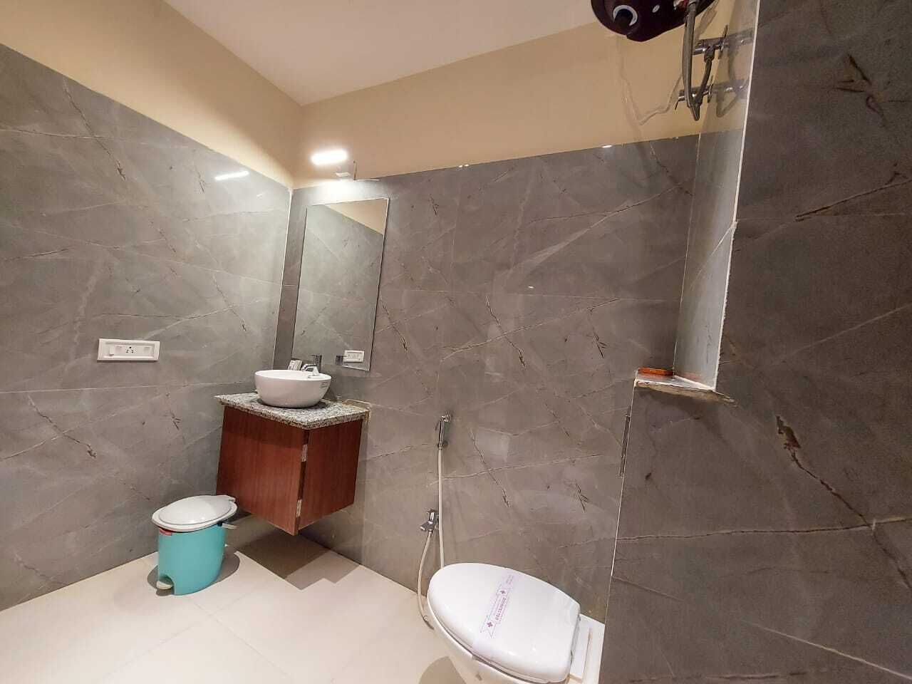 A modern bathroom with a marble floor, a sink with a mirror above it, a toilet, and a shower area.