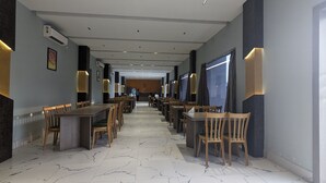A hotel corridor with marble flooring, wooden tables and chairs, and wall-mounted lighting. - PARTH KING BEACH RESORT (Kanthi)