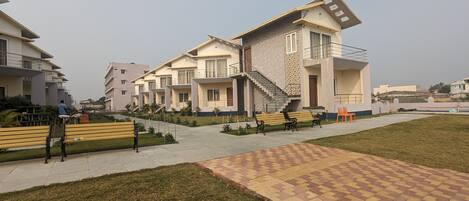 A modern residential complex with multiple two-story buildings, a central courtyard with benches, and a paved walkway.