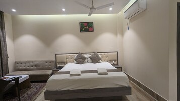 Habitación de hotel con cama, mesita de noche, silla y ventilador de techo.