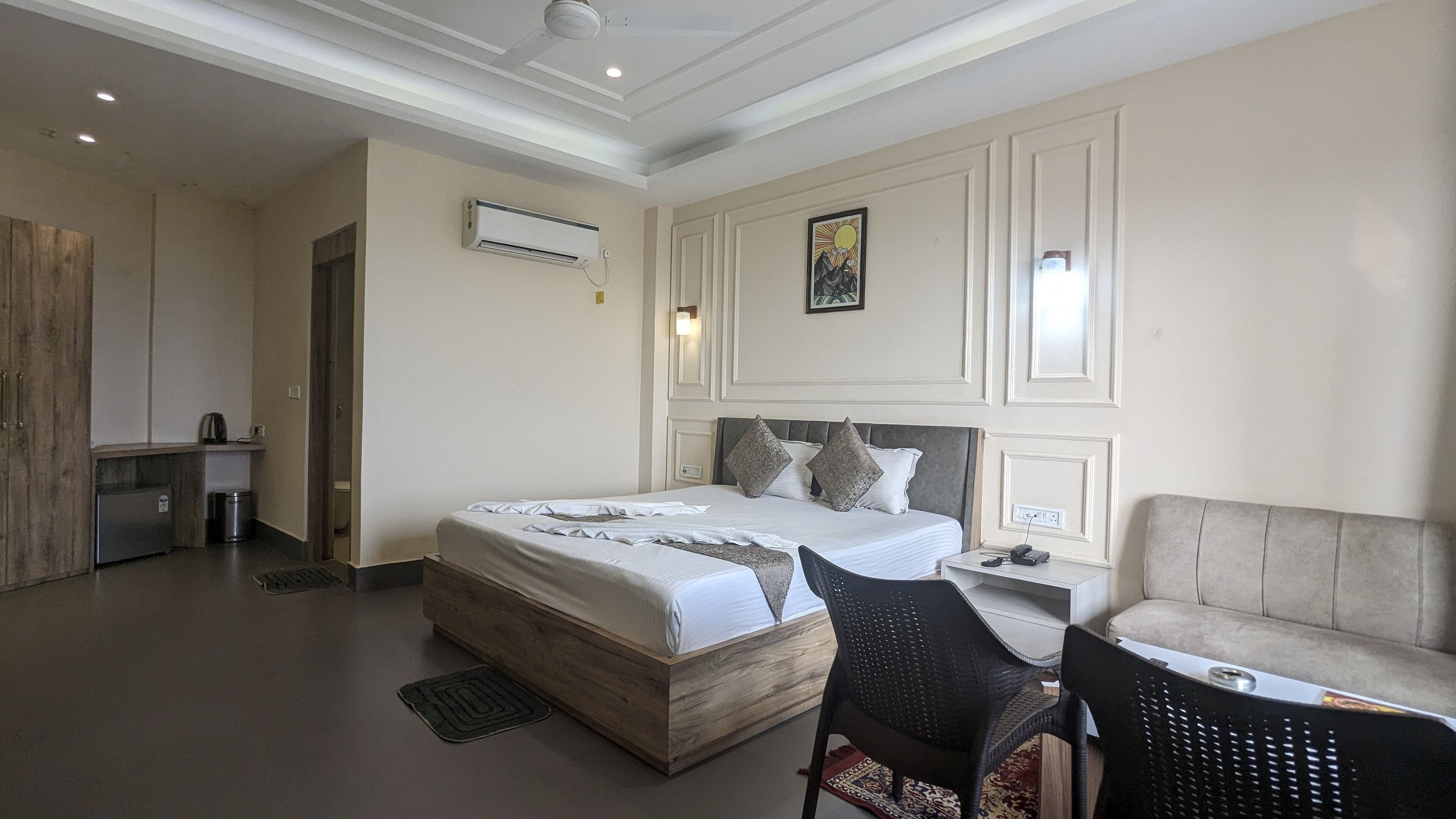 Une chambre d’hôtel avec un lit en bois, une petite kitchenette, un canapé et un bureau avec une chaise.
