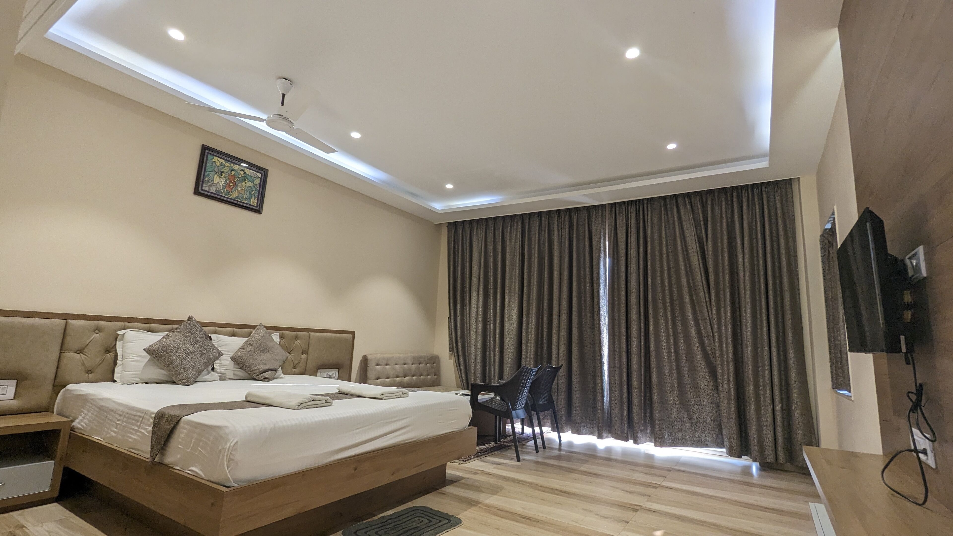 A modern bedroom with a large bed, a desk, and a ceiling fan.