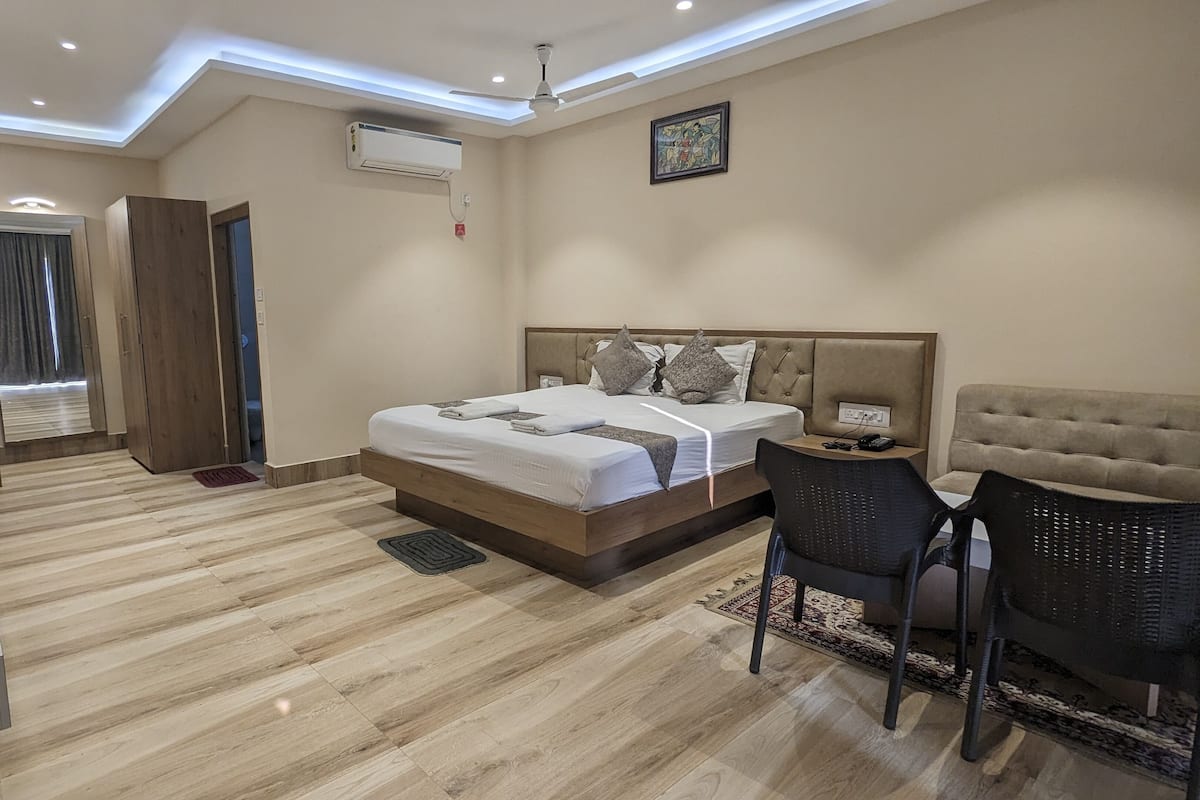 Una habitación de hotel con cama, mesita de noche, silla y televisor.
