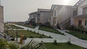 A modern building with multiple floors, outdoor staircases, and a well-maintained garden area. - PARTH KING BEACH RESORT (Kanthi)