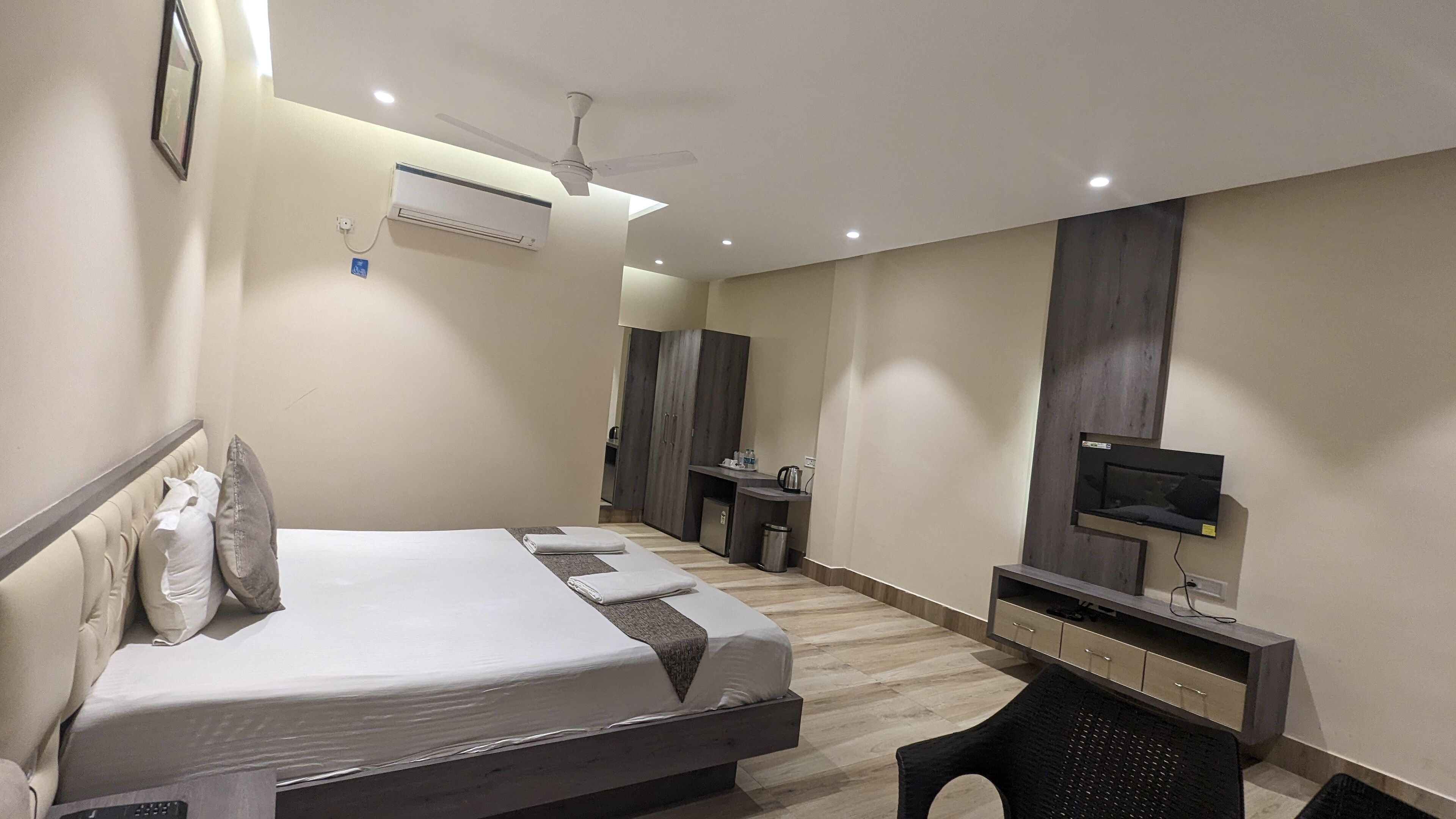A modern hotel room with a bed, a desk, a television, and a wardrobe.