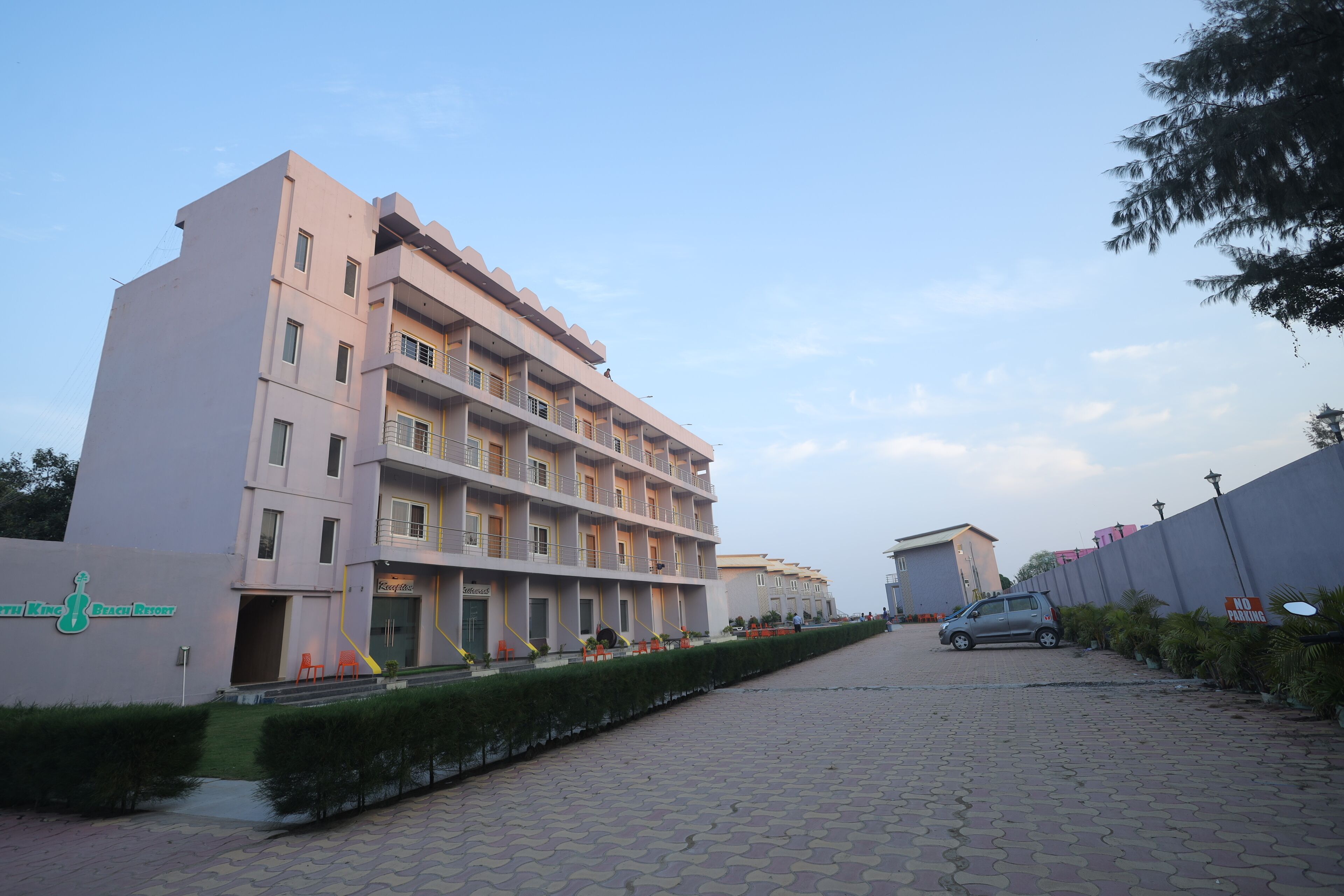 A multi-story hotel with a modern design, featuring balconies and a landscaped pathway.