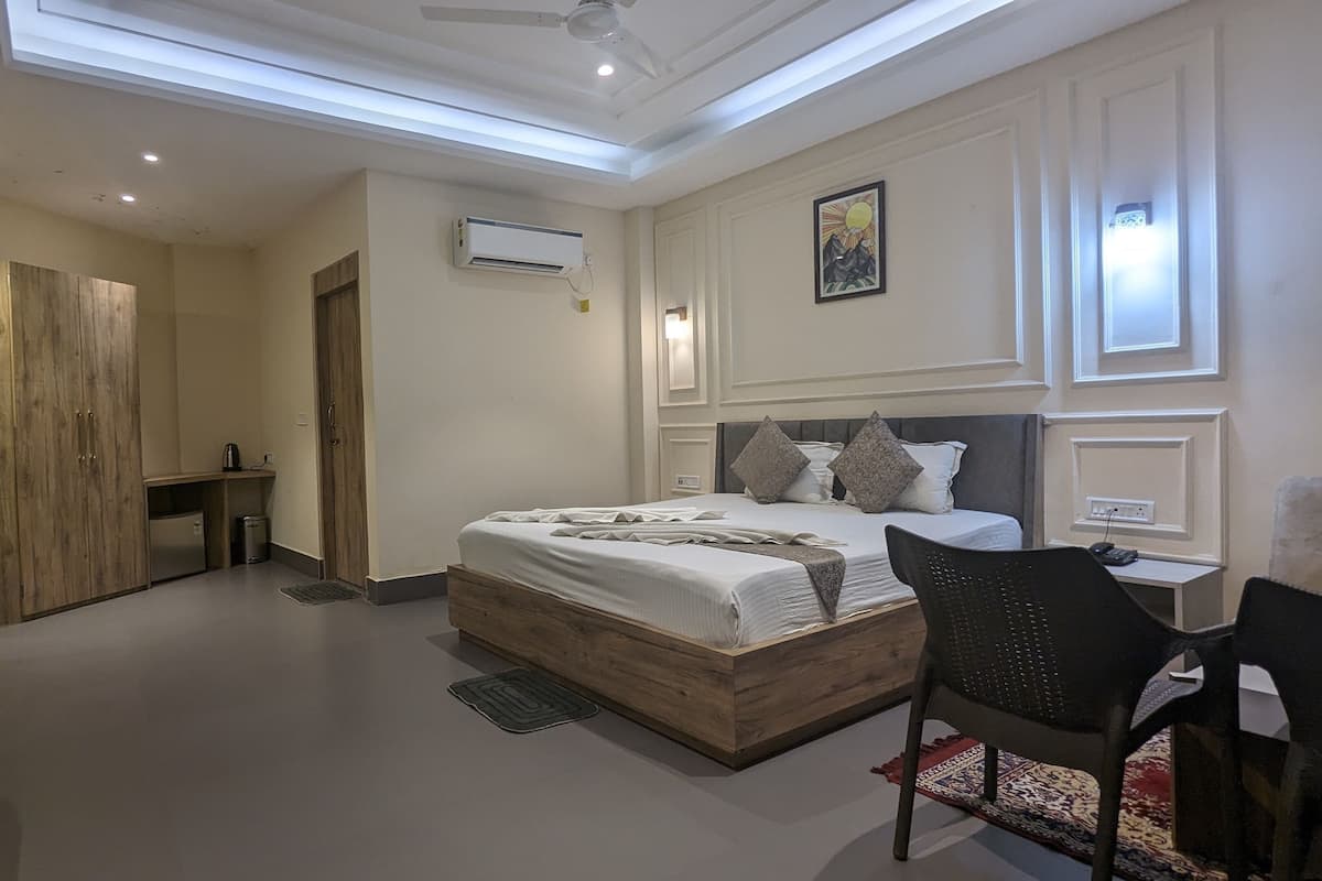 Un dormitorio moderno con una cama grande, un escritorio, una silla y un armario.