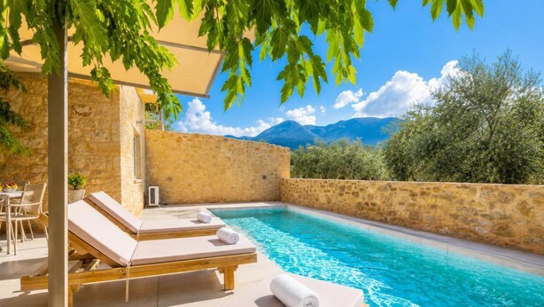 A pool area with lounge chairs and a view of mountains.