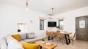 A modern living room with a sofa, coffee table, dining table with chairs, a TV, and a door with a decorative glass panel.