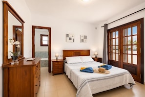 A bedroom with a bed, nightstands, a dresser, a mirror, and a view through a window.