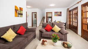Ein geräumiges Wohnzimmer mit zwei Sofas, einem Couchtisch und einer Treppe, die zu einer oberen Etage führt.
