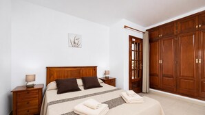 Ein Schlafzimmer mit einem hölzernen Bett, zwei Nachttischen, einem großen Kleiderschrank und einem Wandbild.