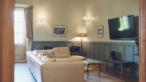 Un soggiorno con divano, tavolino, televisore e un quadro appeso al muro.