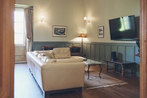 A living room with a sofa, a coffee table, a TV, and a framed picture on the wall. - Idyllic French château surrounded by rolling hills- Chateau de Lassalle (Laplume)