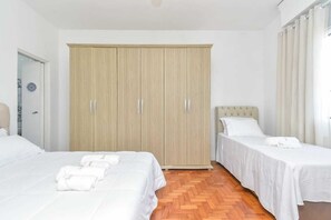 Ein Hotelzimmer mit zwei Betten, einem Kleiderschrank und einem Badezimmer.