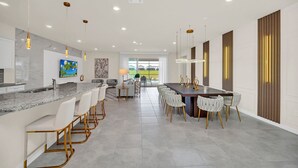A modern kitchen with a marble countertop, bar seating, and pendant lighting. - Fabulous Fun 8 Bed Pool Home with Game Room-4297LA (Davenport)