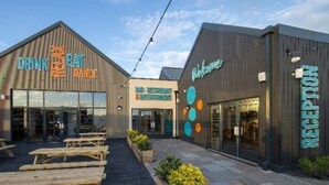 Un edificio con un letrero que dice 'Drink & Eat', una zona de recepción y asientos al aire libre.