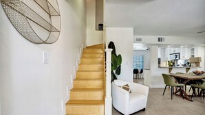 Un escalier menant à une salle à manger où se trouvent une chaise blanche et une table.