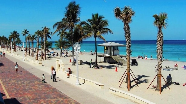 Une plage bordée de palmiers, une tour de surveillance pour les sauveteurs et des gens qui se détendent.
