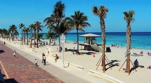 A beach with palm trees, a lifeguard tower, and people relaxing.