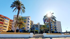 Ett hotell vid stranden med flera våningar, palmer och en klar himmel.