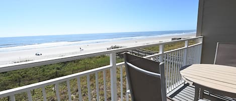 A balcony with a view of the beach and ocean.