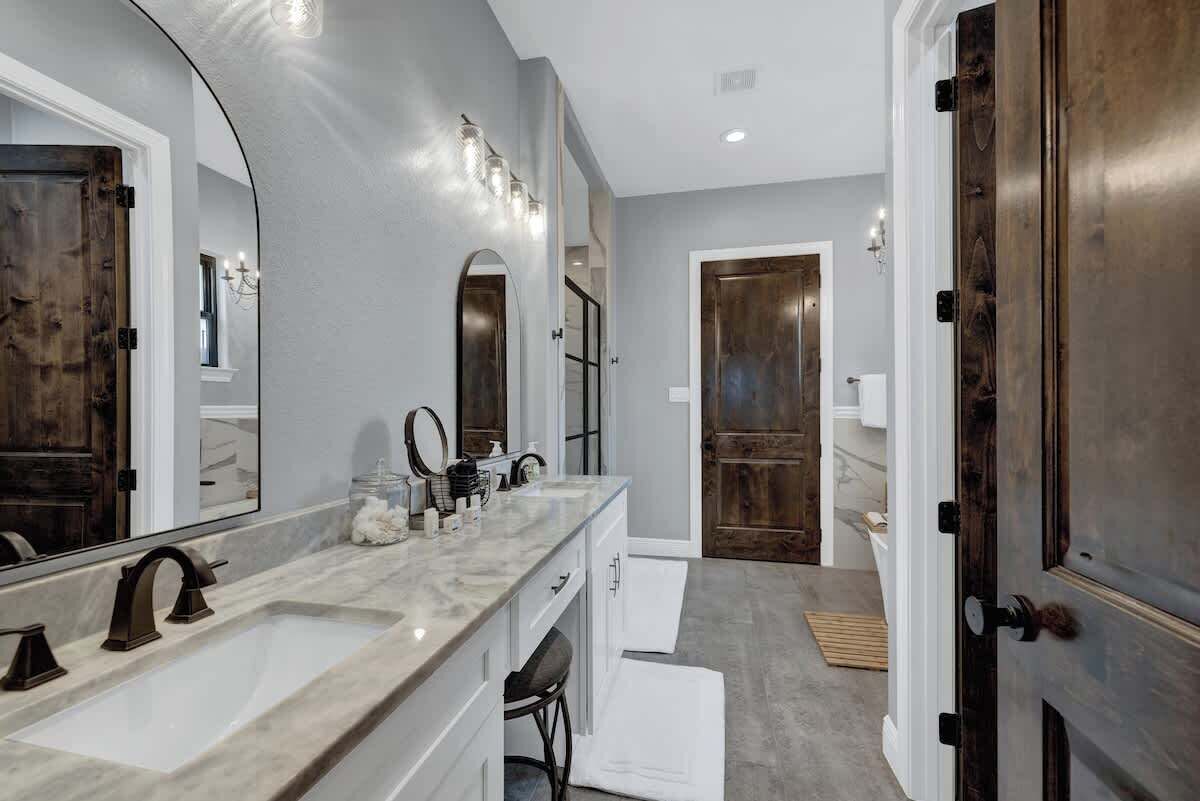 Une salle de bain moderne avec un grand miroir, deux lavabos et une douche à l’italienne.