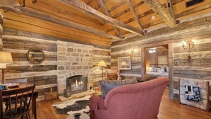 A rustic interior with a stone fireplace, wooden beams, and a cozy seating area. - Coco at Sunset Valley Ranch (Fredericksburg)