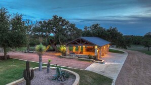 A rustic building with a covered porch, surrounded by a landscaped garden with cacti and a gravel path leading to it. - 7Cs Sunset Valley Ranch (Fredericksburg)