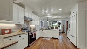 A kitchen with white cabinets, a wooden floor, and a window with a view. - Sunset Valley Ranch (Fredericksburg)