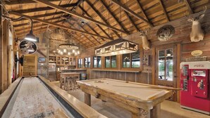 A wooden bar area with a pool table, a billiards table, and a vintage Coca-Cola refrigerator. - Sunset Valley Ranch (Fredericksburg)