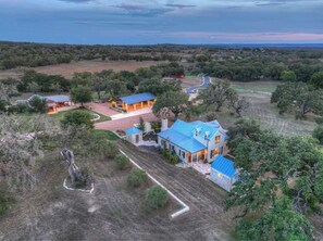 A large estate with multiple buildings, a winding road, and a surrounding landscape. - Sunset Valley Ranch (Fredericksburg)