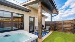 Uma casa moderna com hidromassagem, um alpendre coberto e cerca de madeira.