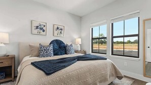 Quarto com uma cama grande, duas mesas de cabeceira, uma janela com vista e duas obras de arte penduradas na parede.