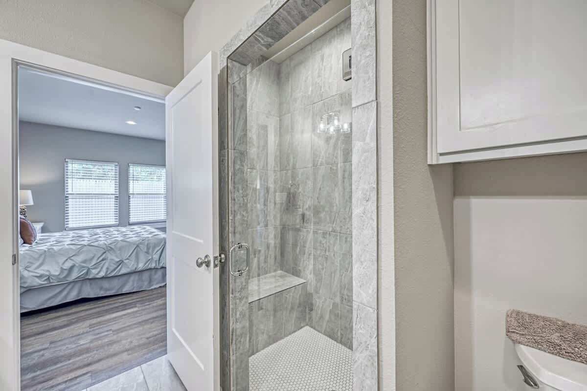 A modern bathroom with a glass-enclosed shower, a white sink, and a visible toilet.