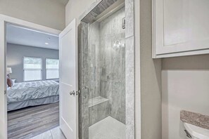 A modern bathroom with a glass-enclosed shower, a white sink, and a visible toilet. - The Ricardo (Fredericksburg)