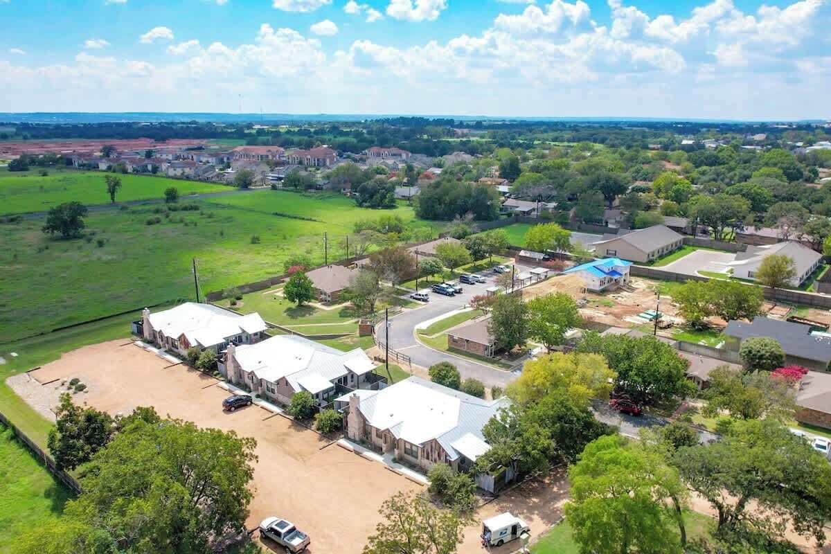 Vista aérea de una zona residencial con varias casas, un campo extenso y un estacionamiento.