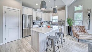 Una cocina moderna con armarios blancos, electrodomésticos de acero inoxidable y una isla grande con taburetes de bar.
