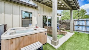 Un patio trasero con un jacuzzi, muebles de jardín y una cerca de madera.