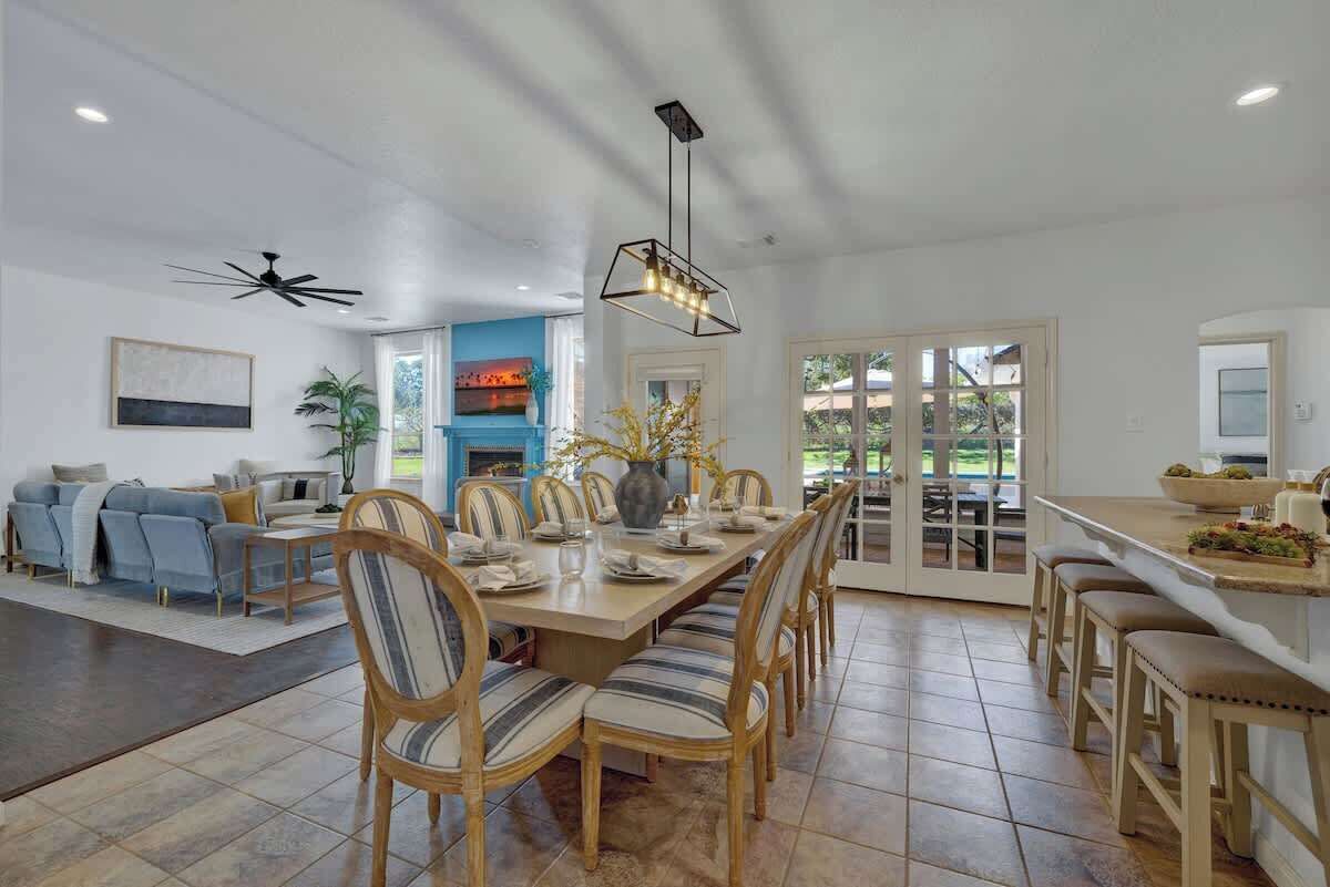 Un vaste espace dédié à la salle à manger, avec une longue table en bois, des chaises à motifs rayés et un luminaire suspendu au design moderne.